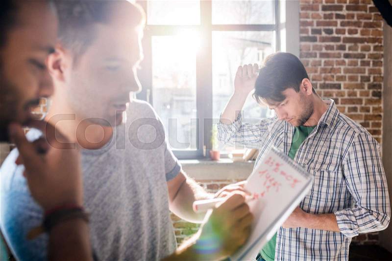 Young professionals working on new business project in small business office, stock photo