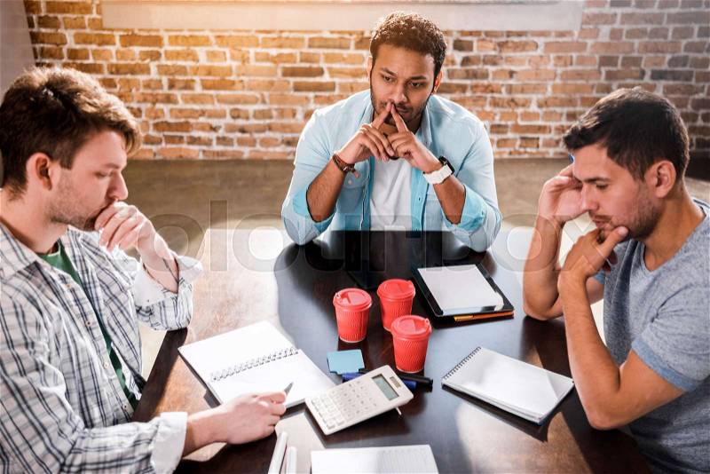Young concentrated men working on project at small office meeting , stock photo