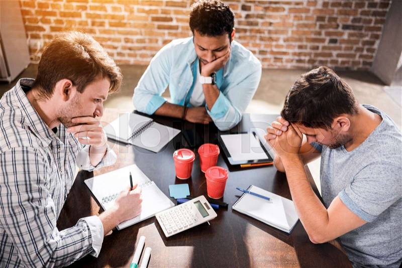 Young concentrated men working on project at small office meeting , stock photo