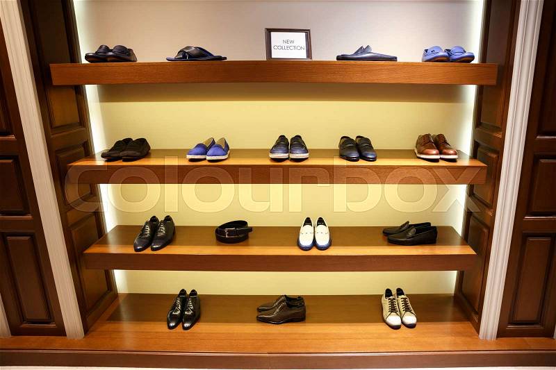 Row of man\'s difeerent shoes on four wooden shelves, stock photo