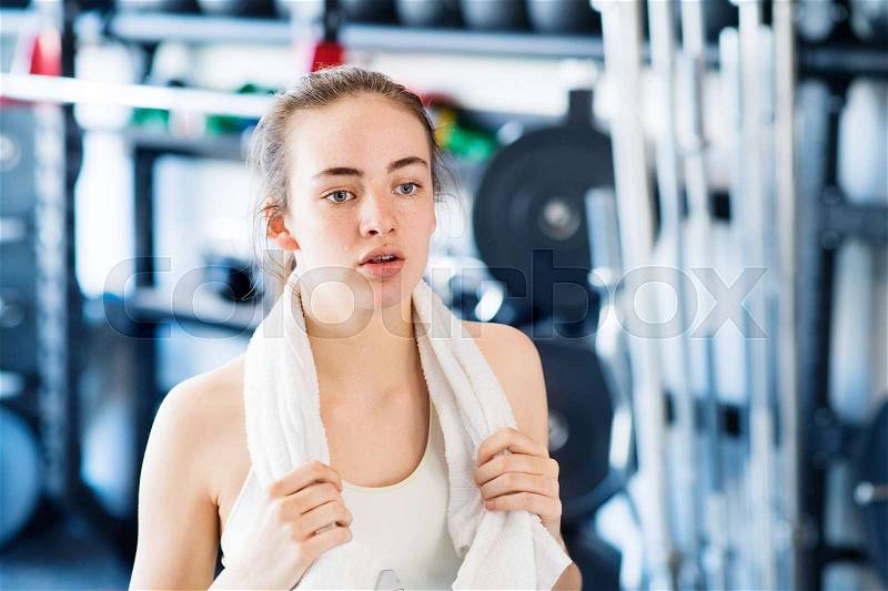 Beautiful young fit woman in gym towel around her neck, resting, stock photo