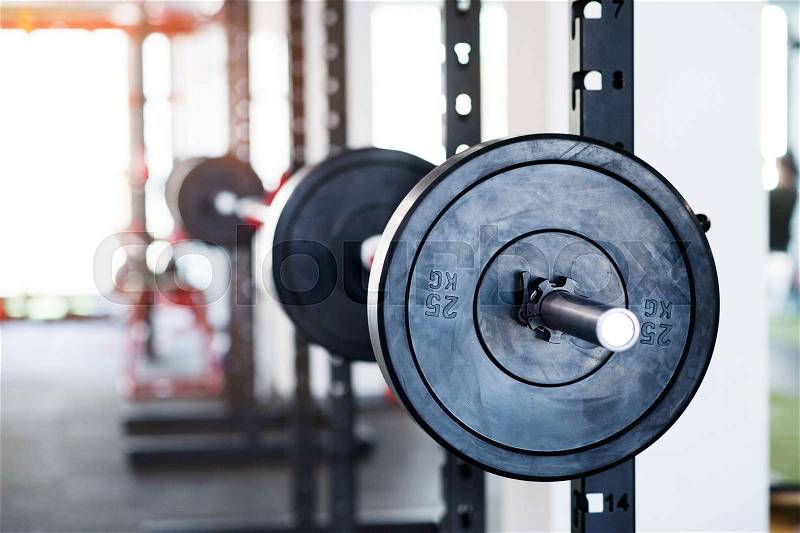 Close up of metal heavy barbell in holder in modern gym. Weight training equipment, stock photo