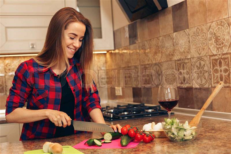 Cooking healthy. Young woman preparing healthy salad and smiling, stock photo