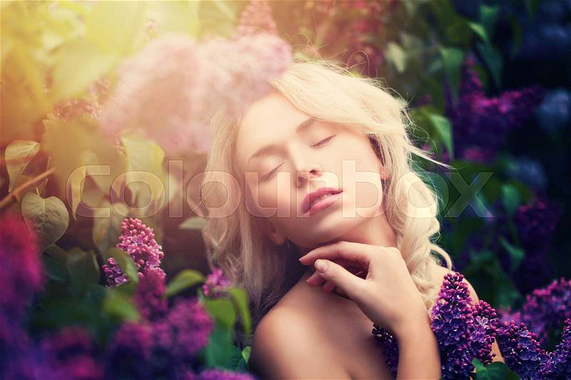 Cute Woman with Summer Light and Lilac Flowers Outdoors. Natural Beauty in Sunny Flowers Garden, stock photo