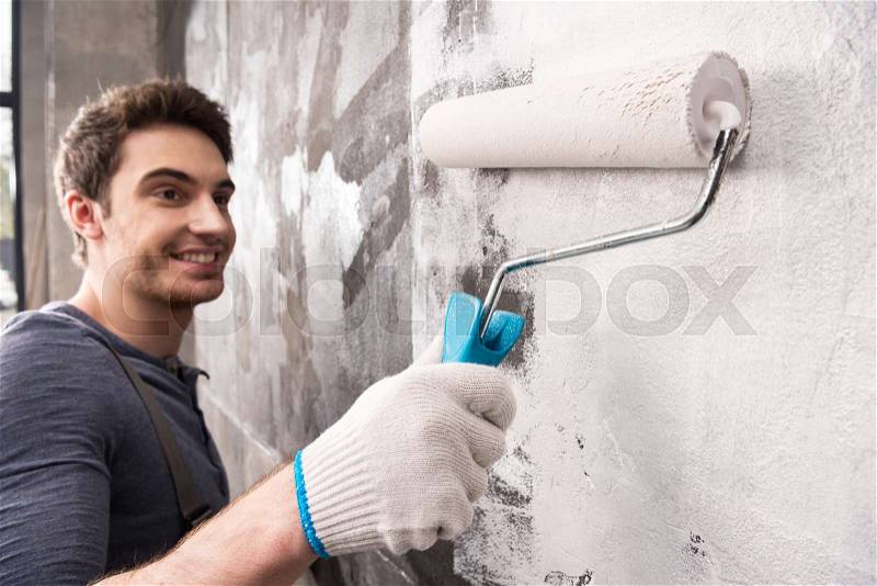 Young man painting wall, renovation home concept, stock photo