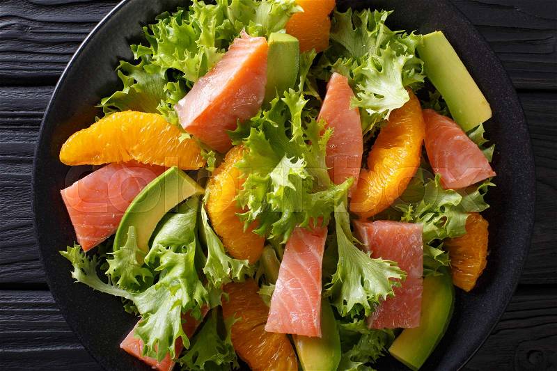 Beautiful food: salad of salted salmon, oranges, avocado and lettuce close-up on a plate on a table. horizontal view from above , stock photo