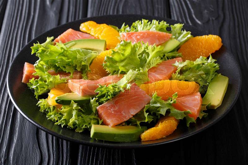 Beautiful food: salad of salted salmon, oranges, avocado and lettuce close-up on a plate on a table. horizontal , stock photo