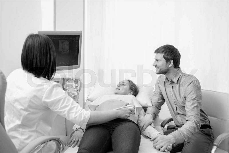 Monochrome shot of a doctor moving ultrasound probe on the stomach of a pregnant woman healthcare medicine sonogram pregnancy couples support relationships appointment hospital clinic, stock photo
