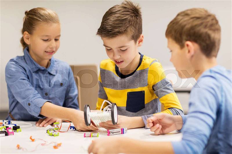Education, children, technology, science and people concept - group of happy kids building robots at robotics school lesson, stock photo