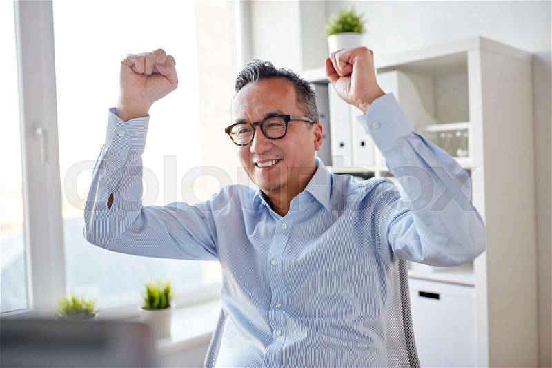Business, people and success concept - happy businessman celebrating victory at office, stock photo