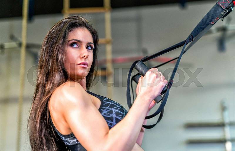 Beautiful brunette girl using weights at gym, stock photo