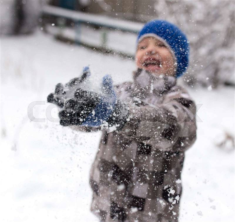 Boy playing with snow on nature in winter, stock photo