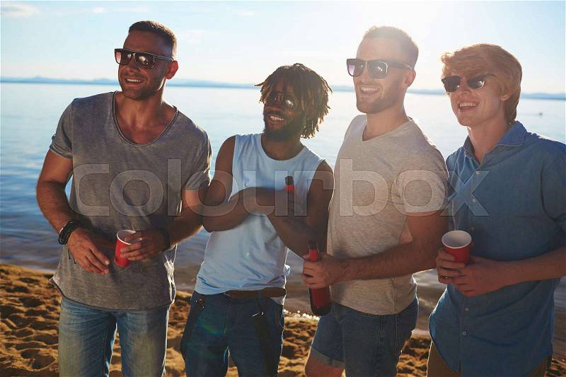 Multi-ethnic group of guys in sunglasses enjoying beach party, stock photo