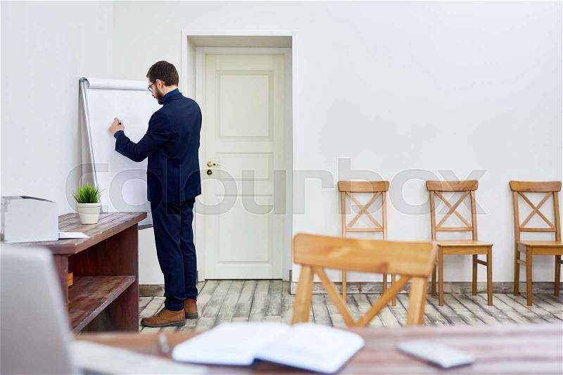 Portrait of businessman writing on white board in office, thinking and planning ideas, stock photo