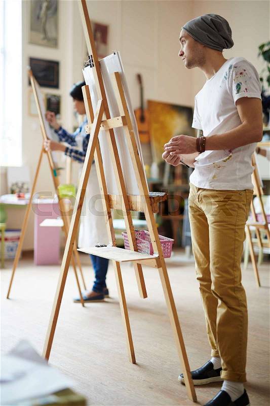 Learner of art-school standing by easel, stock photo