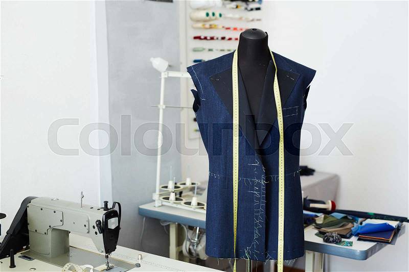 Tailoring studio interior: mannequin and working tables with sewing machines in empty workshop, stock photo