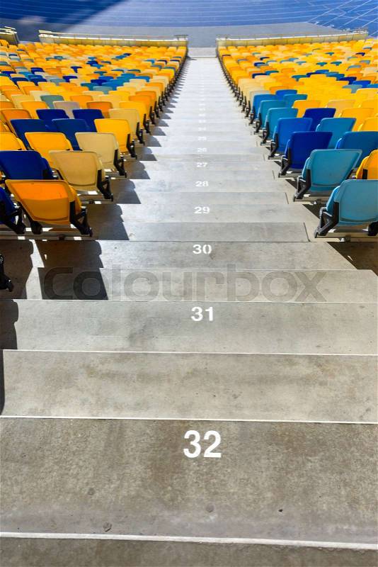Rows of yellow and blue stadium seats and stadium stairs, stock photo