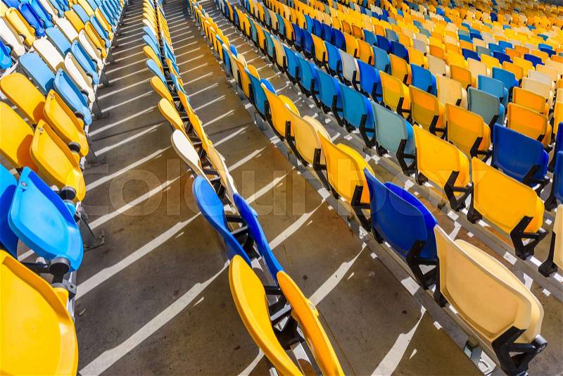 Rows of yellow and blue stadium seats on soccer stadium, stock photo