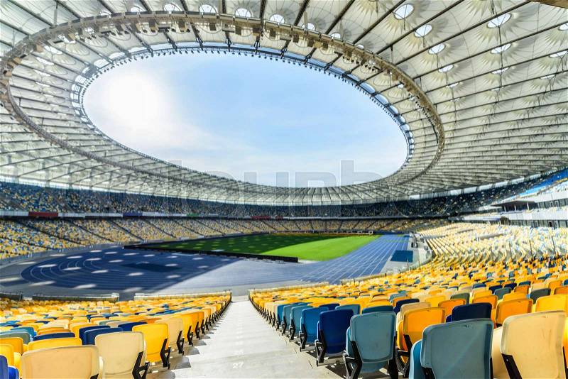 Rows of yellow and blue stadium seats on soccer field stadium, stock photo