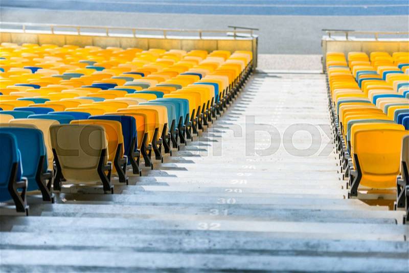 Rows of yellow and blue stadium seats and stadium stairs, stock photo
