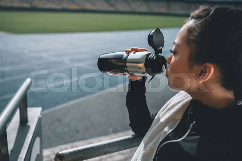 Asian sportswoman drinking water and towel on running track on stadium, stock photo