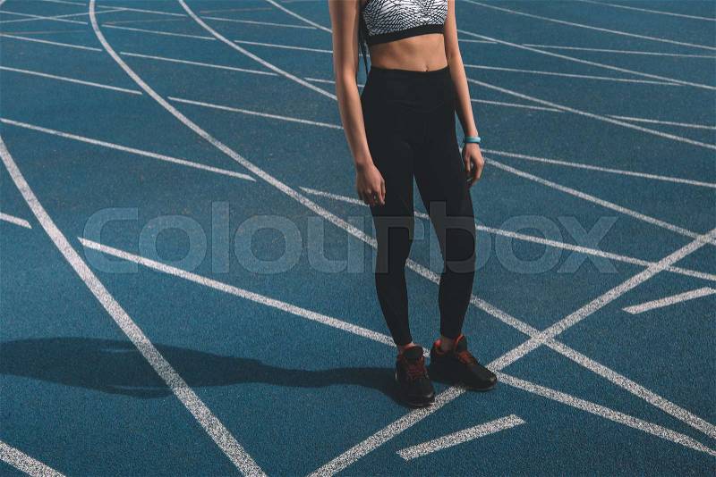 Young sportswoman standing on running track stadium, running woman tired concept, stock photo