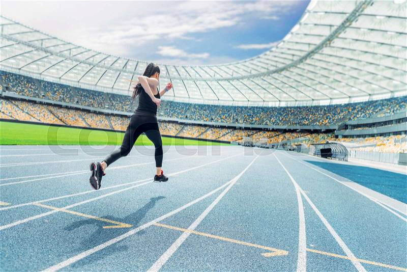Young fitness woman in sportswear running on running track stadium, stock photo