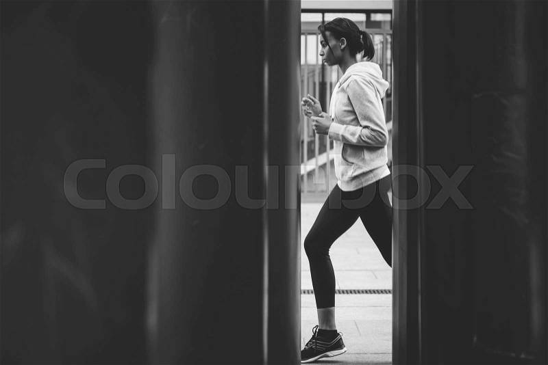 Side view of young fitness woman in sportswear jogging on stadium, black and white photo, stock photo