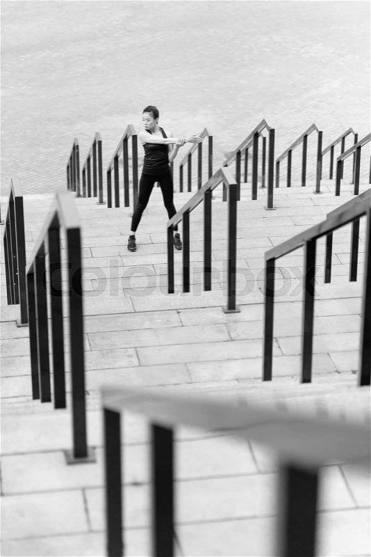 Black and white photo of sporty young woman exercising on stadium stairs , stock photo