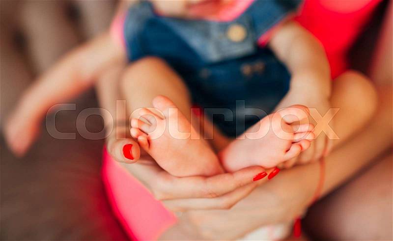 Little legs of the child, lies on the hands of the parents. Newborn baby, stock photo
