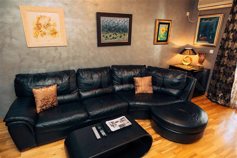 Black leather sofa in the apartment. Interior living room, stock photo