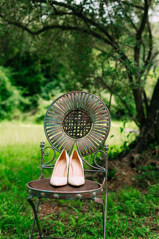 Bride's shoes on a metal chair vintage in olive forest, stock photo