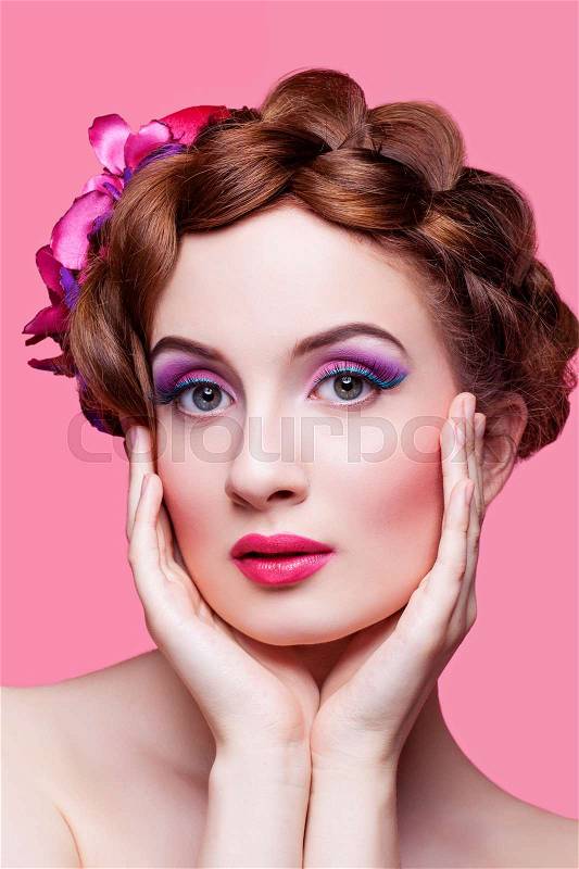 Beautiful young woman with red braided hair, bright make-up and small fancy hat over pink background. Pin up style. Copy space, stock photo