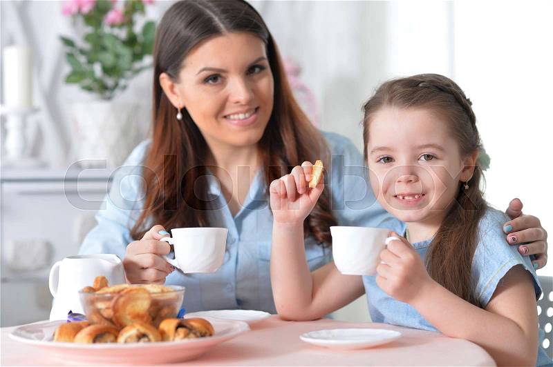 Mom and daughter having breakfast together at the table, stock photo