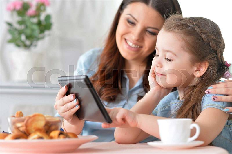 Mom and daughter having fun together at the table, stock photo