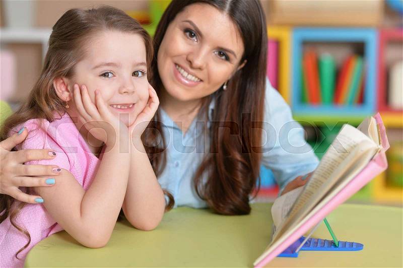 Mom and daughter study together at the table, stock photo