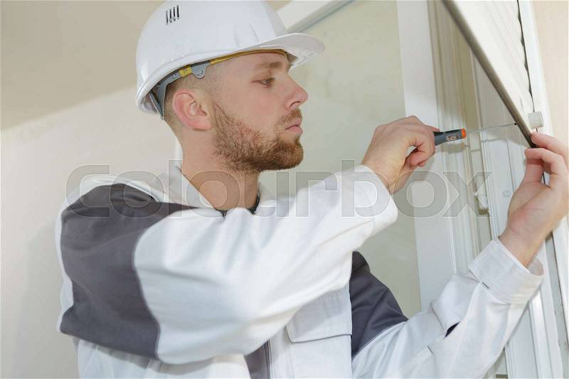 Young contractor installing window blinds, stock photo