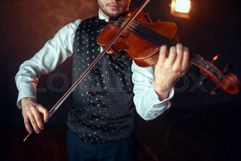 Portrait of male fiddler playing classical music on violin. Violinist man with musical instrument, stock photo