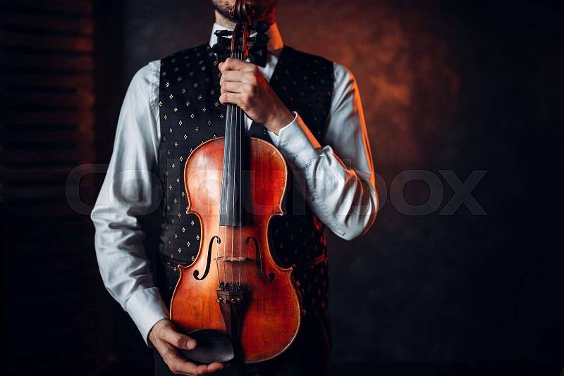 Portrait of male person holding wooden violin. Fiddler with musical instrument, stock photo