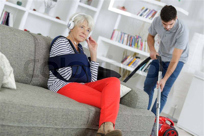 Young man home help cleaning ladys living room, stock photo