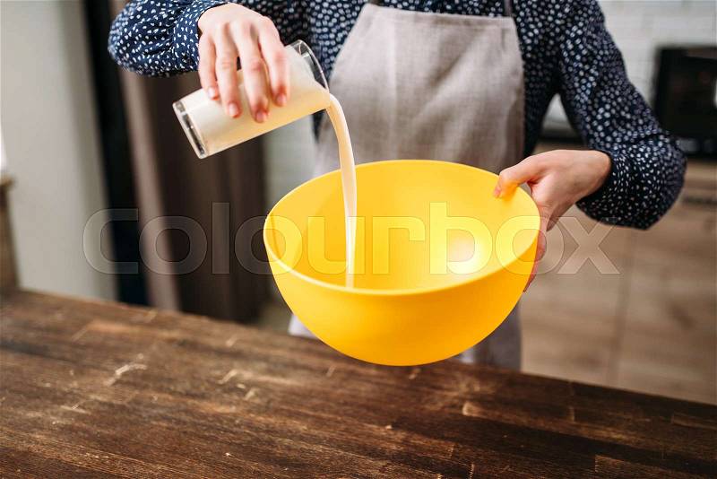 Female person adds cream into a bowl, homemade cake cooking. Fresh tasty dough preparation, stock photo