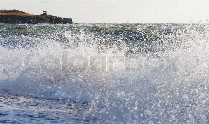 Sea surf great wave break on coastline and cape with pavilion at a distance, stock photo
