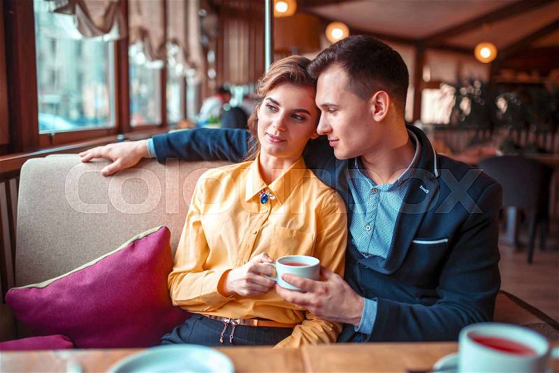 Love couple hugs and looking at the window in restaurant. Man and woman beautiful relationship, stock photo