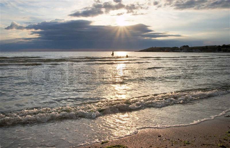 Children bathe and play in evening sea, stock photo