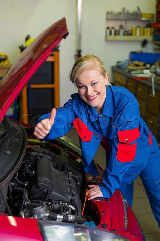 A young woman as a mechanic in an auto repair shop. rare professions for women. car will be repaired in the workshop, stock photo