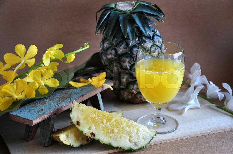 Fresh pineapple with glass of pineapple juice on wooden board, stock photo