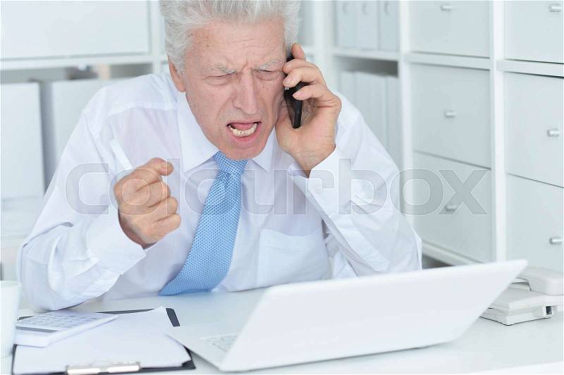 Elderly businessman working in the office with laptop, stock photo