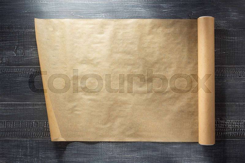 Scroll of brown paper at wooden background texture, stock photo