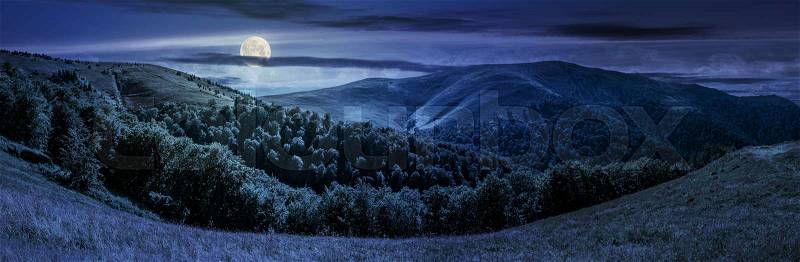 Panoramic summer landscape under dark sky with clouds. hillside meadow on Borzhava mountain ridge in Carpathians at night in full moon light, stock photo