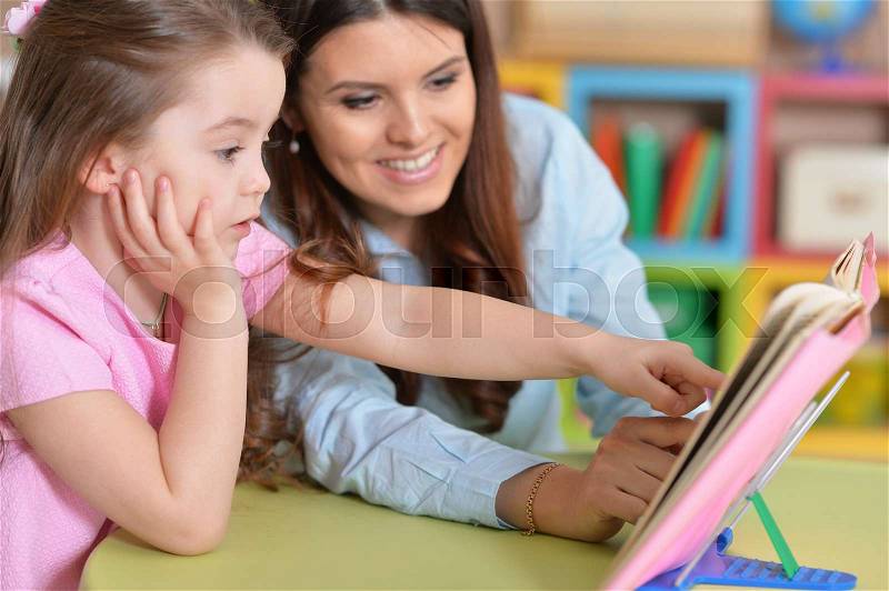 Mom and daughter study together at the table, stock photo